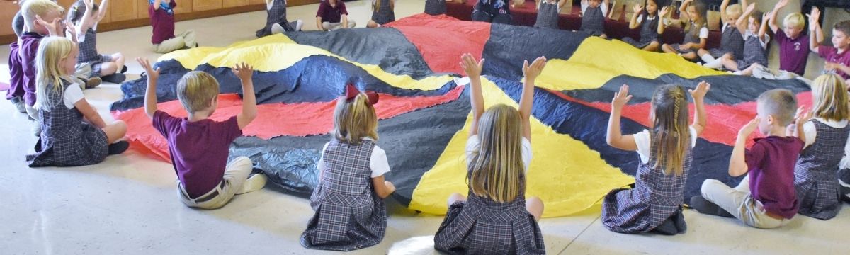 Paideia at a Glance Banner students in music class playing parachute games